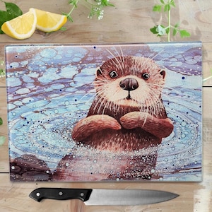 May include: A glass chopping board featuring a brown and white otter swimming in blue water with white bubbles. The otter is looking at the camera with its paws crossed.