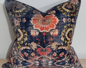 May include: A square cushion with a distressed, vintage-style design. The cushion has a dark blue background with a floral pattern in red, yellow, and beige. The cushion is made of a soft fabric and would suit a living room or bedroom.