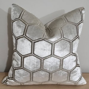 Könnte beinhalten: Ein weißes Kissen mit einem geometrischen Muster aus braunen Sechsecken.