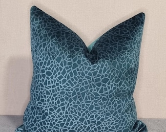 Puede incluir: Almohada de terciopelo azul turquesa con un patrón geométrico. La almohada es cuadrada y tiene un respaldo azul claro.
