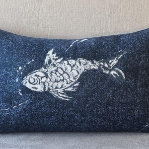 May include: A blue rectangular pillow with a white fish design. The fish is stylized and has a textured appearance.