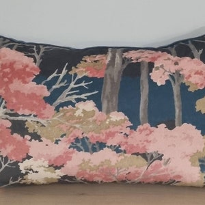 Puede incluir: Una almohada rectangular con fondo azul oscuro y un patrón floral con flores rosas, blancas y beige. La almohada tiene un borde gris oscuro.