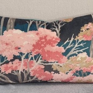 Puede incluir: Una almohada decorativa con un fondo azul oscuro y un patrón floral. Las flores son rosas y blancas con ramas grises.