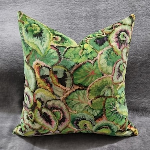 May include: A decorative throw pillow with a vibrant botanical print. The pillow features a repeating pattern of green, yellow, and pink leaves. The pillow is square and appears to be made of a soft fabric.