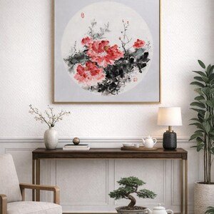 Puede incluir: Una obra de arte enmarcada con una pintura de acuarela de peon&iacute;as rojas y hojas verdes oscuras. La obra de arte est&aacute; sobre un fondo circular gris claro. El marco es dorado y la obra est&aacute; colgada en una pared blanca.