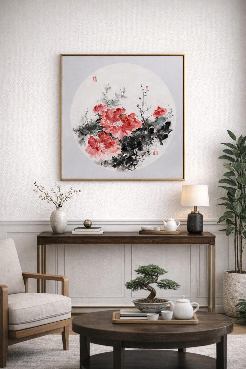 Puede incluir: Una obra de arte enmarcada con una pintura de acuarela de peon&iacute;as rojas y hojas verdes oscuras. La obra de arte est&aacute; sobre un fondo circular gris claro. El marco es dorado y la obra est&aacute; colgada en una pared blanca.
