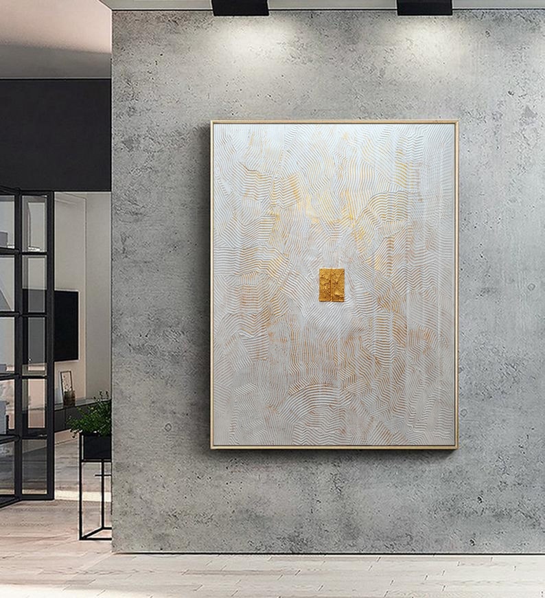 May include: A rectangular wall art piece featuring a white textured surface with intricate, wavy, embossed lines and subtle gold accents. A small, solid gold-coloured rectangular element is positioned in the centre of the canvas, framed in a thin gold border.