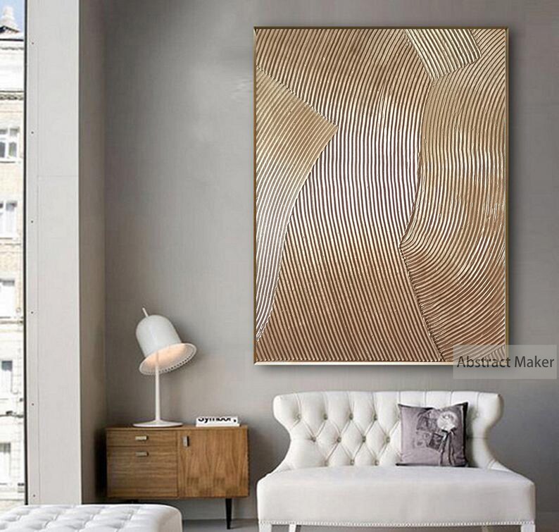 Puede incluir: Impresi&oacute;n de arte abstracto con un patr&oacute;n geom&eacute;trico marr&oacute;n y blanco. La impresi&oacute;n est&aacute; enmarcada en un marco dorado fino y cuelga de una pared gris claro sobre un sof&aacute; blanco.