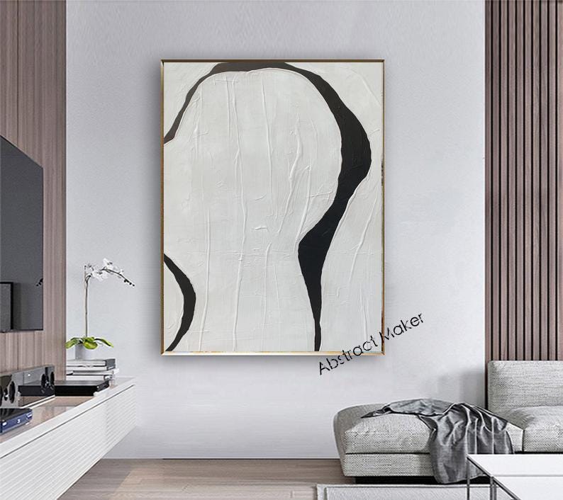 May include: Abstract painting with a white textured background and bold black curved lines. The artwork is framed in a gold-colored frame and hangs on a white wall. The text "Abstract Maker" is visible in the lower right corner.