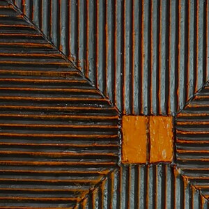 May include: A close-up of a wooden panel with a geometric pattern. The panel is painted in shades of black and orange. The pattern is created by a series of parallel lines that intersect at right angles.