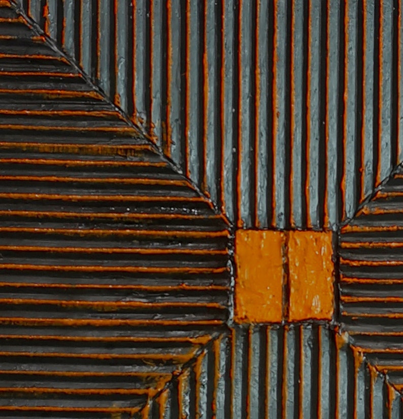 May include: A close-up of a wooden panel with a geometric pattern. The panel is painted in shades of black and orange. The pattern is created by a series of parallel lines that intersect at right angles.