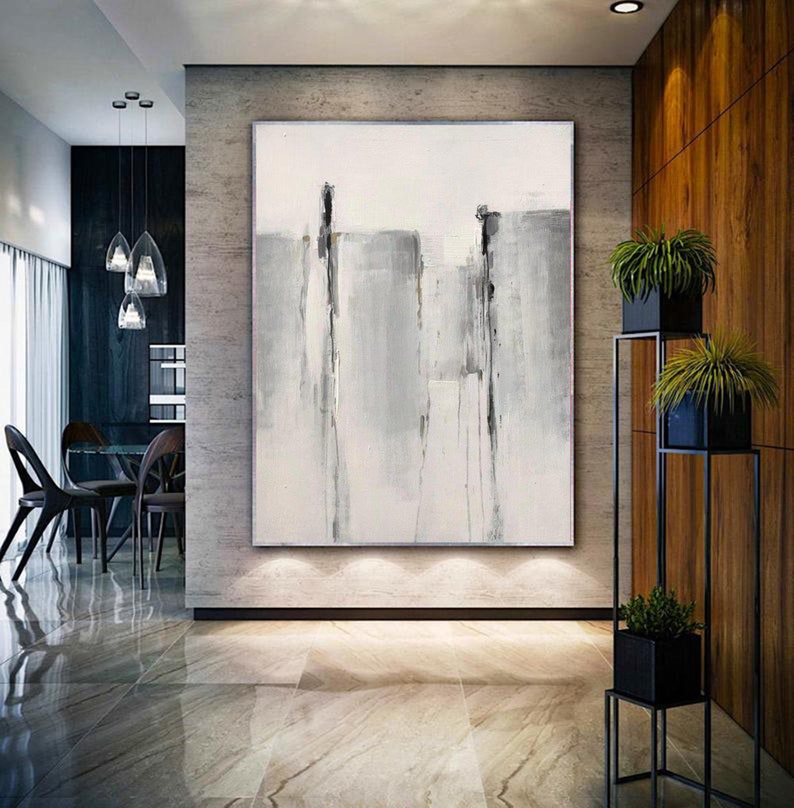 May include: Abstract painting with vertical gray and white brushstrokes on a white canvas. The painting is hanging on a wall in a modern home.