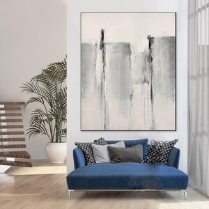 May include: Abstract painting in shades of gray and white with black lines. The painting is hanging on a white wall in a modern living room with a blue sofa and a potted plant.
