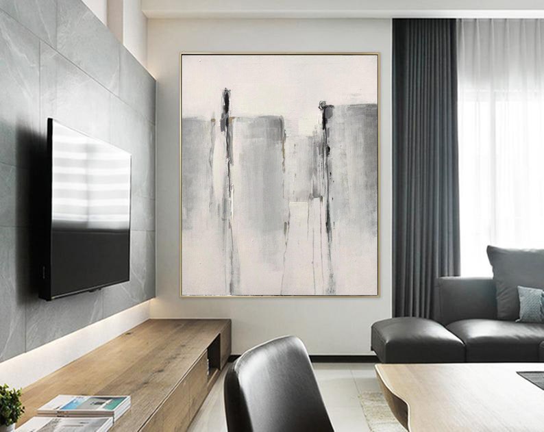 May include: Abstract painting with gray and white brushstrokes on a white canvas. The painting is framed in a thin gold frame and is hanging on a wall in a modern living room.