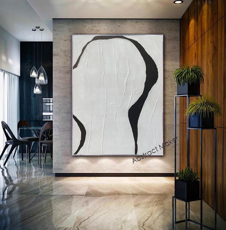 May include: Large abstract painting with a white textured background and bold black curved lines. The artwork is displayed in a modern interior setting, enhancing the room's aesthetic. The painting is signed "Abstract Maker".