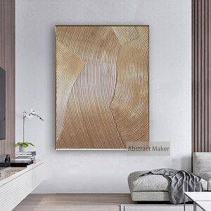 Puede incluir: Impresi&oacute;n de arte abstracto con un esquema de color dorado y blanco. La impresi&oacute;n presenta una serie de l&iacute;neas curvas que crean un patr&oacute;n ondulado. La impresi&oacute;n est&aacute; enmarcada en un marco fino dorado. "Abstract Maker" est&aacute; impreso en la esquina inferior derecha de la impresi&oacute;n.
