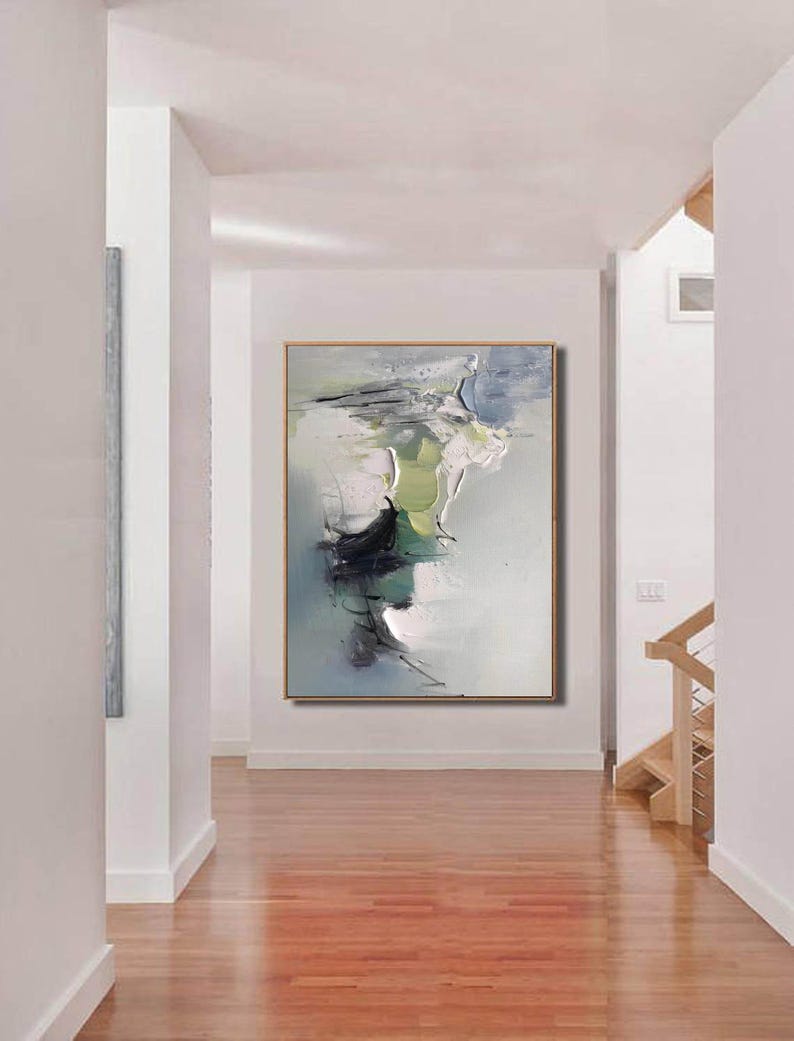 May include: Abstract painting with shades of green, blue, and white. The painting is framed and hanging on a white wall in a hallway.