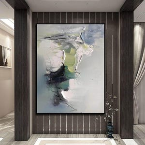 May include: Abstract painting with shades of green, blue, and white. The painting has a textured, brushstroke effect and is framed in a black frame.