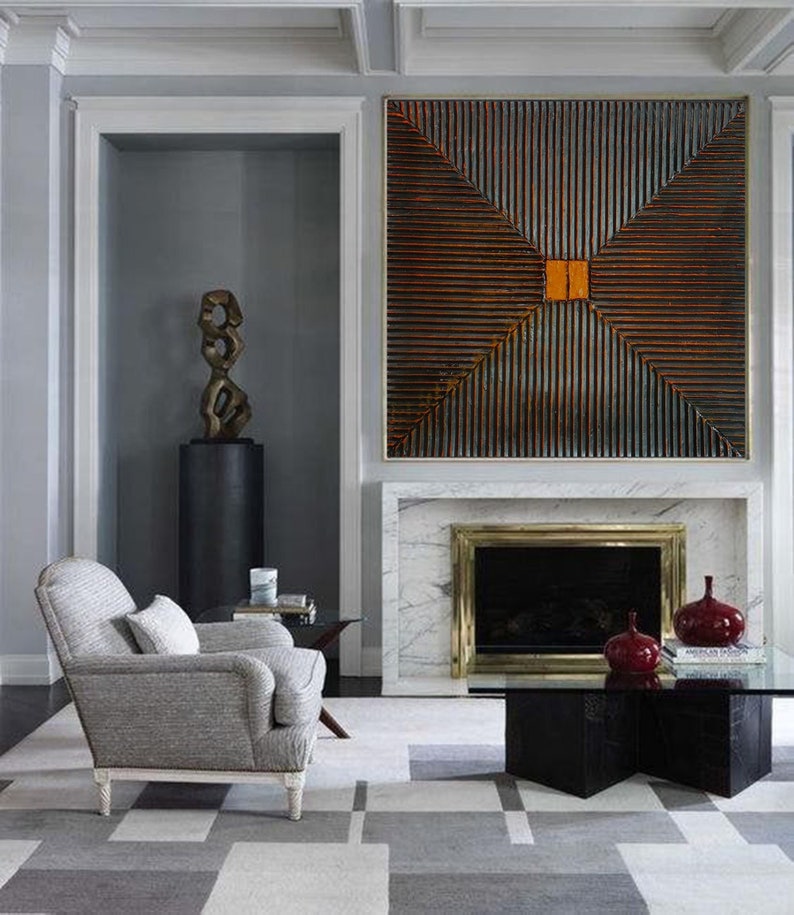 May include: A modern living room with a gray armchair, a black coffee table, and a fireplace with a large abstract artwork above it. The artwork is made of wood and has a geometric pattern with a central orange square.