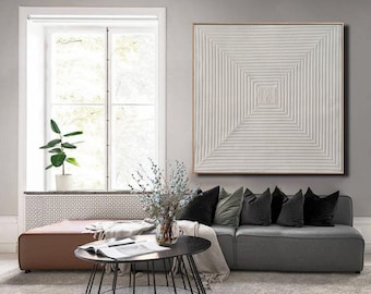 Puede incluir: Un sofá seccional gris con cojines de terciopelo suave y una pintura abstracta blanca encima. El sofá está en una sala de estar con una mesa de café y una ventana en el fondo.