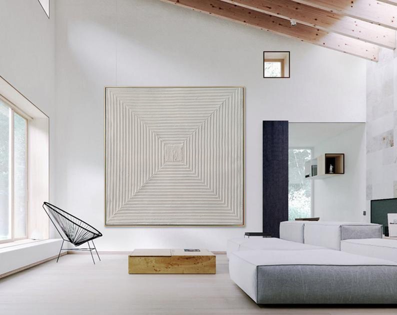 May include: A white, square, abstract painting with a geometric pattern of lines. The painting is hanging on a white wall in a modern living room with a white couch and a black chair.