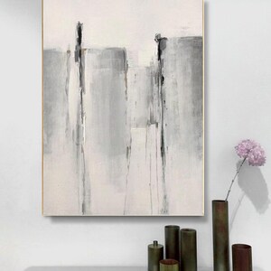 May include: Abstract painting with gray and white vertical stripes on a white background. The painting is framed in a thin gold frame.