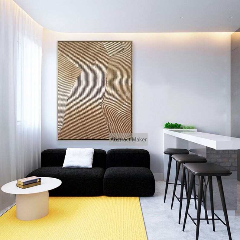 Puede incluir: Un dise&ntilde;o de interior de sala de estar con un sof&aacute; seccional negro, una mesa de caf&eacute; blanca, una alfombra amarilla y una gran pintura abstracta con l&iacute;neas doradas y marrones. La pintura est&aacute; colgada en una pared blanca. Hay tres taburetes de bar negros en el fondo.