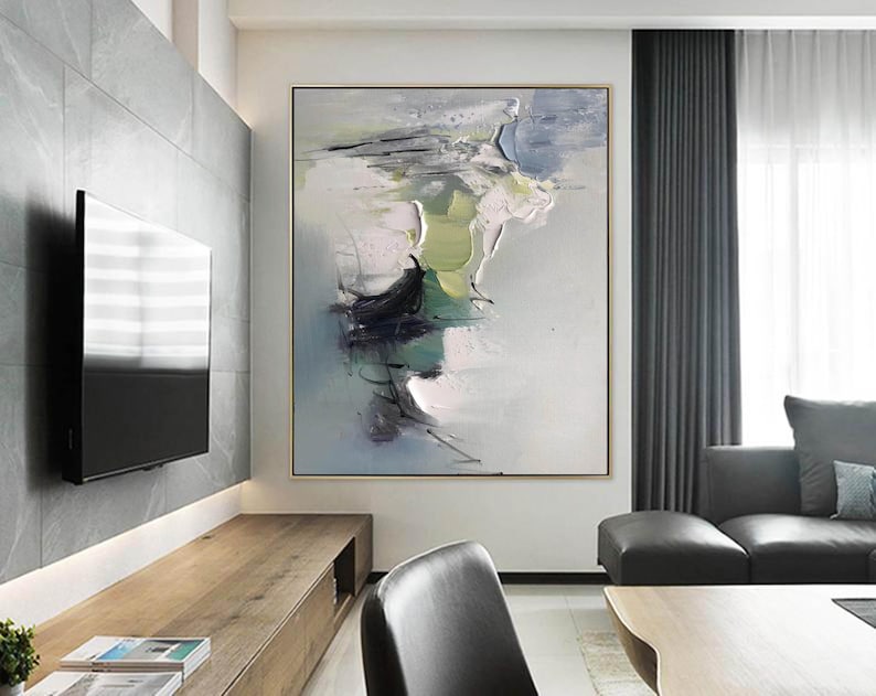 May include: Abstract painting with shades of green, blue, and white. The painting is on a canvas and is framed in a gold frame. The painting is hanging on a wall in a living room.