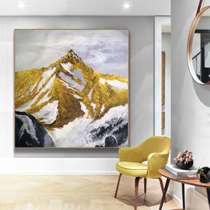 May include: Abstract painting of a mountain range with gold, white and black paint. The mountain peaks are covered in snow and the sky is a light blue.