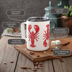 May include: White stainless steel travel mug with a red lobster design. The mug has a comfortable handle, a leak-proof slide lid, and is double-walled and vacuum insulated. It holds 12 ounces and keeps drinks hot or cold for hours. The mug is a sustainable alternative to disposable cups.