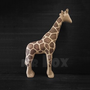May include: A wooden giraffe figurine with a brown and tan patterned design. The giraffe is standing on a black surface.