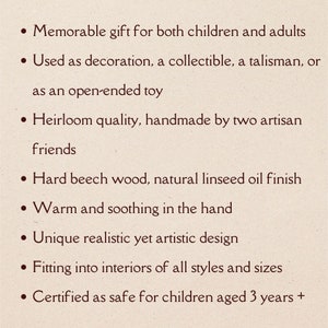 May include: A list of features for a wooden toy. The toy is described as a memorable gift for both children and adults, heirloom quality, handmade by two artisan friends, made of hard beech wood with a natural linseed oil finish, warm and soothing in the hand, unique realistic yet artistic design, fitting into interiors of all styles and sizes, and certified as safe for children aged 3 years and up.