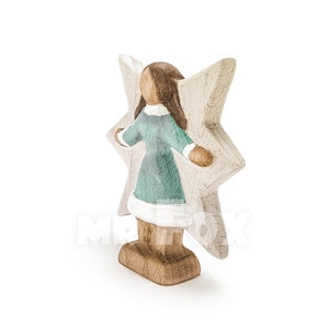 Wooden winter fairy figurine. Side view. White background. Blue dress. White showflake shaped wings. Long dark brown hair.