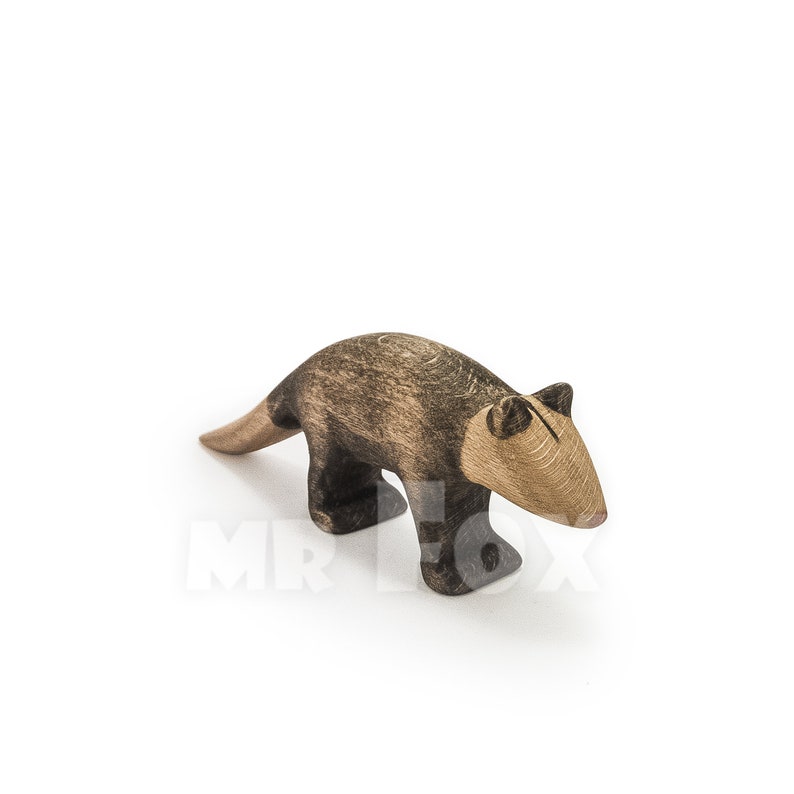 May include: A wooden anteater figurine with a light brown snout and tail, and a dark brown body and legs. The toy is made of wood and has a simple, stylized design, perfect for children's play or as a decorative item.