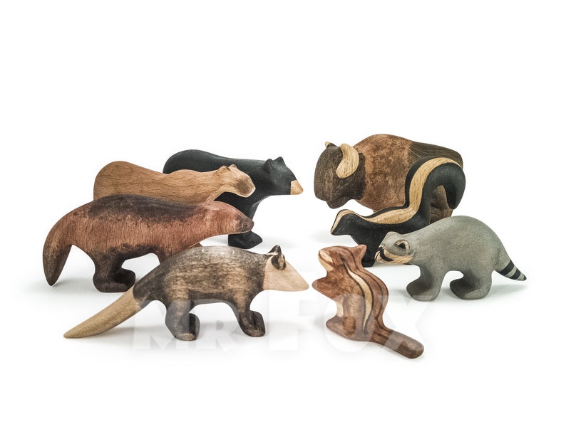 May include: A collection of wooden animal figurines, including a bear, bison, skunk, raccoon, and chipmunk. The figurines are hand-carved and painted in natural colors, showcasing the wood grain. These toys are designed for imaginative play.