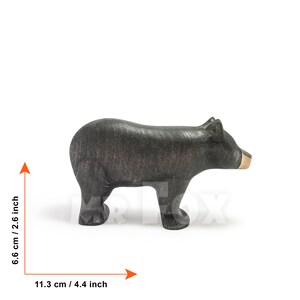 May include: A handcrafted wooden bear figurine, painted black with a natural wood snout. The bear measures 4.4 inches long and 2.6 inches tall. This decorative item is suitable for home decor or as a collectible.