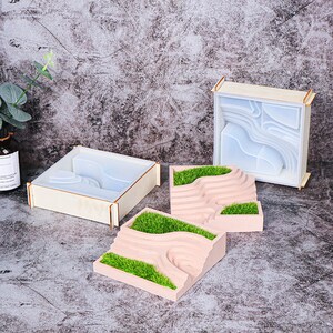 Peut inclure: Trois moules en bois pour la création d'artisanat en résine. Les moules sont en forme de paysage avec des collines et des vallées. Les moules sont présentés avec de l'herbe artificielle verte à l'intérieur.