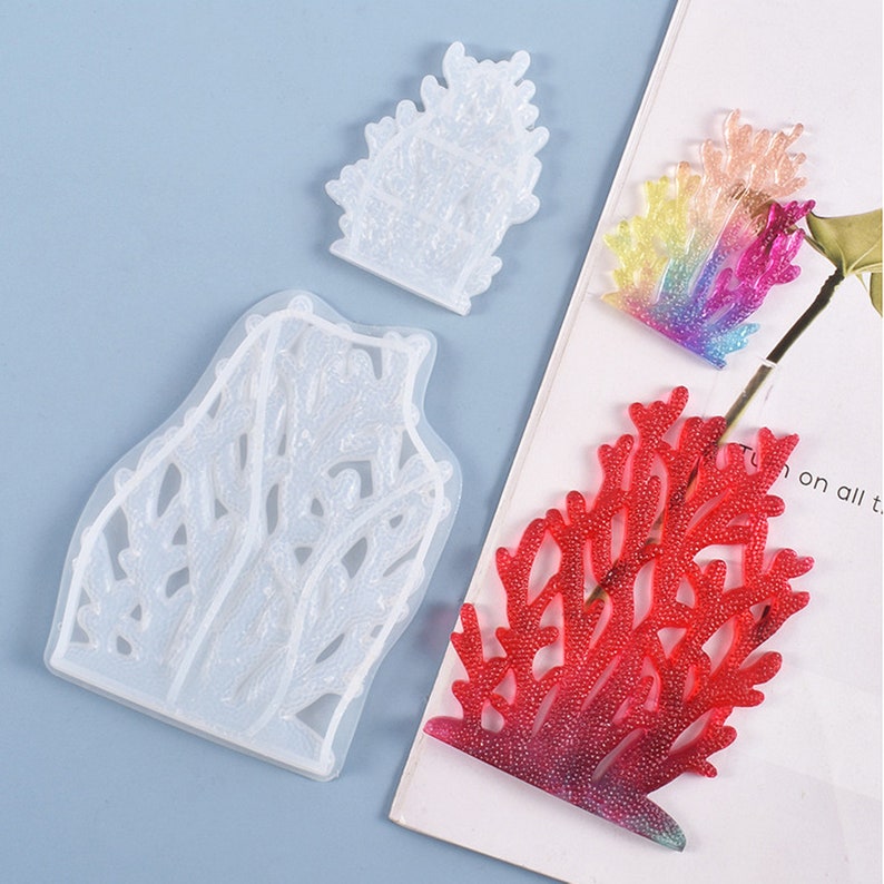 Puede incluir: Un molde de silicona transparente y piezas de coral de resina acabadas. El molde es de dos partes, con una forma de coral grande y peque&ntilde;a. Las piezas acabadas son rojas, arco&iacute;ris e iridiscentes.