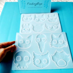 Puede incluir: Dos moldes de silicona transparentes para hacer manualidades de resina. El molde superior tiene seis cavidades: un gato, un conejo, una calavera, un gato, un búho y un gato. El molde inferior tiene cinco cavidades: una calavera, un búho, un gato, una huella de pata y un gato.