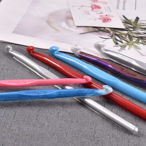 Può includere: Un set di sei ferri da uncinetto in vari colori, tra cui argento, rosa, blu, rosso e viola. I ferri sono etichettati con le loro dimensioni in millimetri: 3,0 mm, 3,5 mm, 4,0 mm, 5,0 mm, 5,5 mm e 6,0 mm.