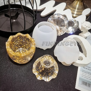 May include: Four silicone molds for resin casting, two are white and two are filled with clear resin and gold flakes. The molds are shaped like a bowl, a dome, and a half-sphere.