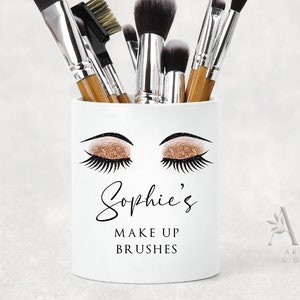 May include: White ceramic makeup brush holder with a gold glitter eye design and the text "Sophie's Make Up Brushes".