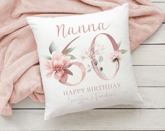 May include: White square pillow with the word "Nanna" in script, a large "60" with floral accents, and the text "HAPPY BIRTHDAY Love Sam & Frankie x". The pillow is on a pink blanket.
