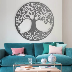 May include: A teal blue sofa with three pillows, two pink and one green, sits in front of a white wall with a large gray metal tree of life wall decor.