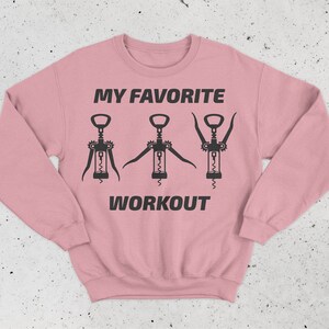 May include: Pink sweatshirt with the text "MY FAVORITE WORKOUT" and three black silhouettes of corkscrews.