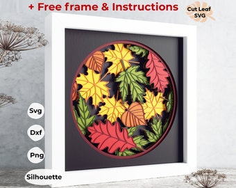 May include: A white frame with a black mat surrounding a round, layered paper art piece. The art features a variety of fall leaves in shades of red, orange, yellow, and green. The text "Cut Leaf SVG" is in the upper right corner of the image.