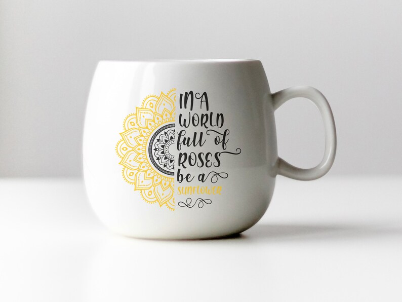May include: White ceramic mug with a yellow and black mandala design and the text "In a world full of roses be a sunflower".