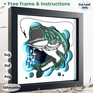 May include: A 3D papercraft model of a bass fish jumping out of the water with a fishing line and hook. The model is made of layered paper and has a blue and green color scheme. The model is framed in a black frame and includes the text "Free frame & Instructions" and "Cut Leaf SVG".