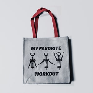 May include: A gray reusable tote bag with red handles. The bag has a black graphic of three corkscrews with the text "MY FAVORITE WORKOUT" printed on it.