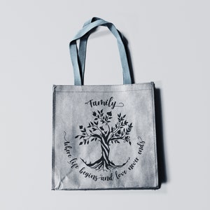 May include: A gray tote bag with blue handles features a black silhouette of a tree with the text "Family where life begins and love never ends".